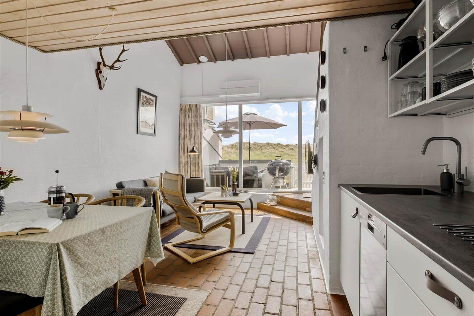 Kitchen with dining area and view to terrace with grill and umbrella.