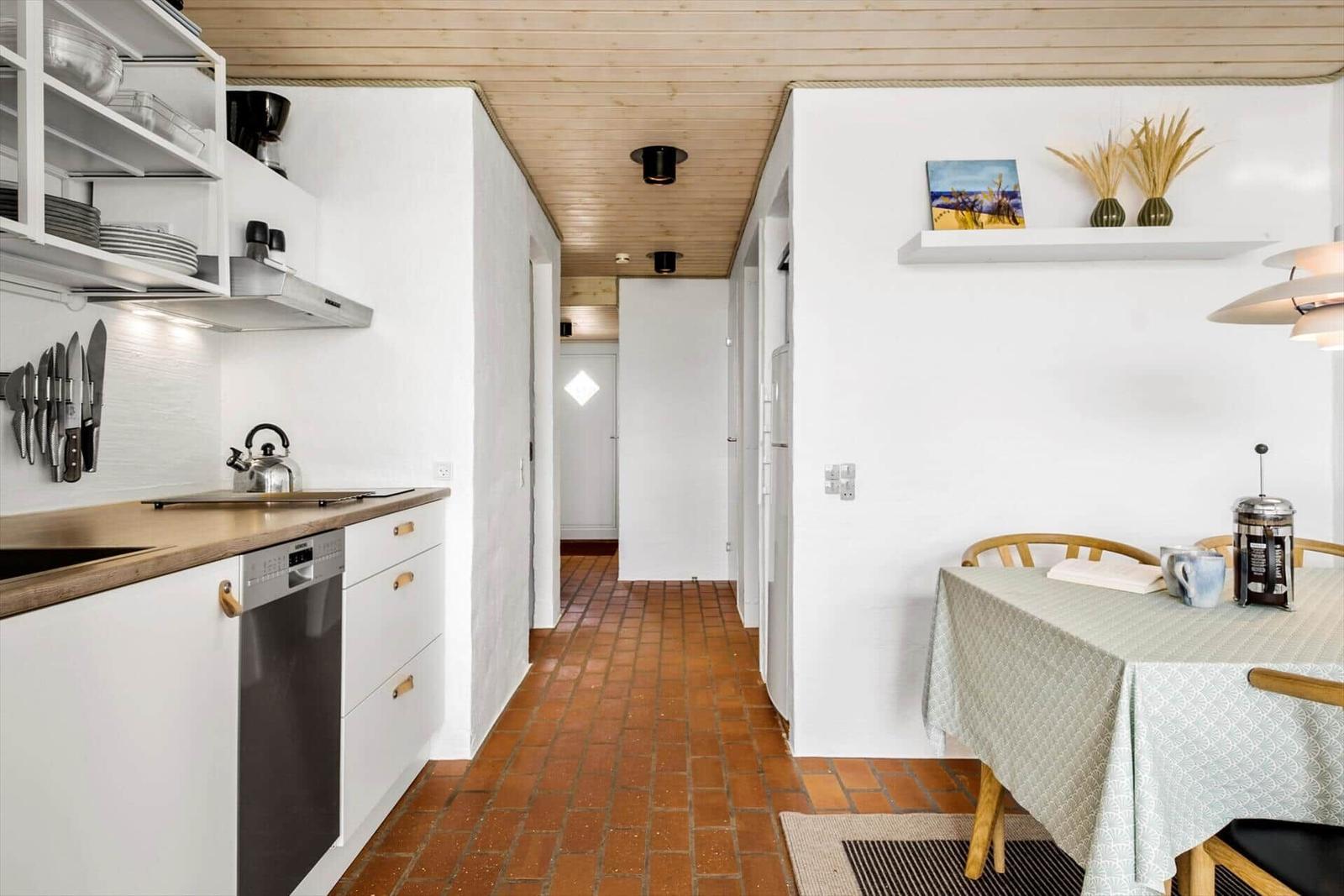 Kitchen and dining area with wooden floor and white walls.