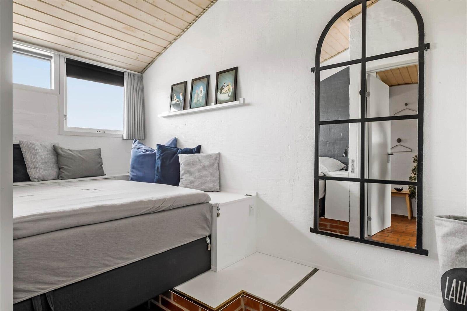 Bedroom with bed, window, and mirror on the wall.