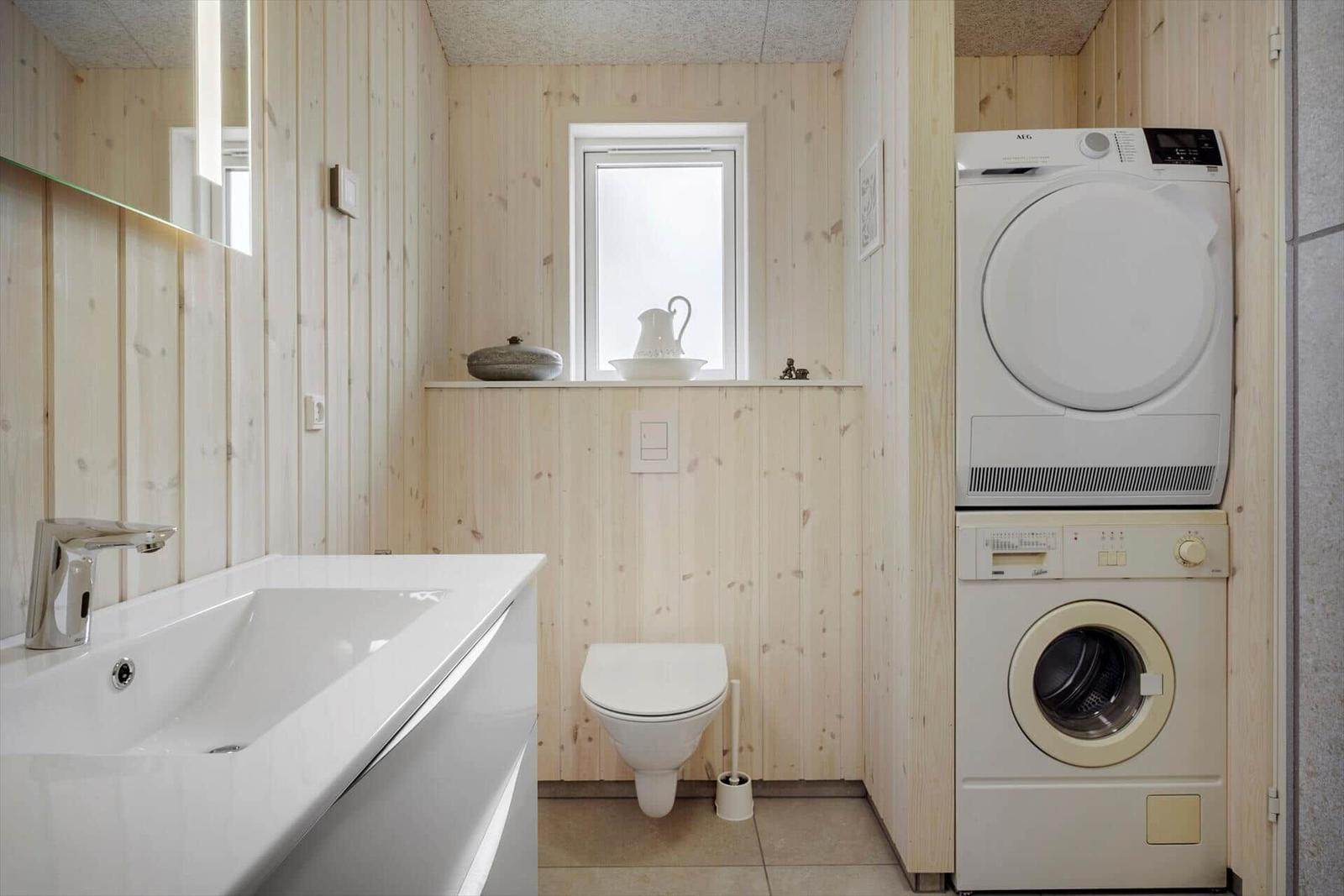 Badezimmer mit Waschmaschine und Trockner, Toilette und Fenster