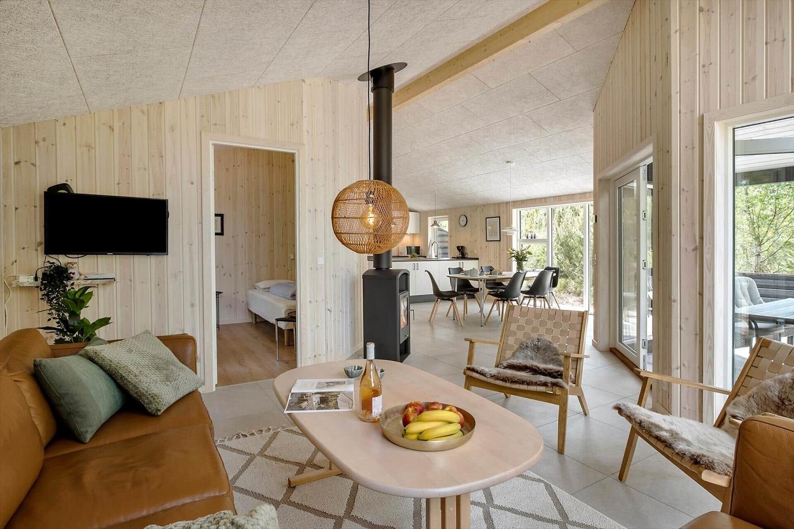 Wohnbereich mit Holzwand, Sofa, Esstisch und Kaminofen.