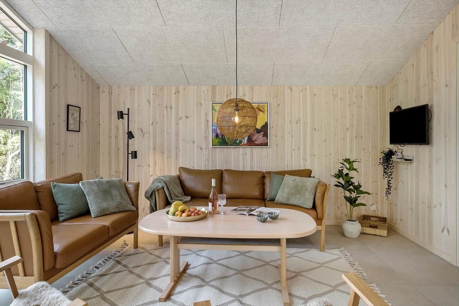 Wohnzimmer mit Holzwand, Sofa und Esstisch