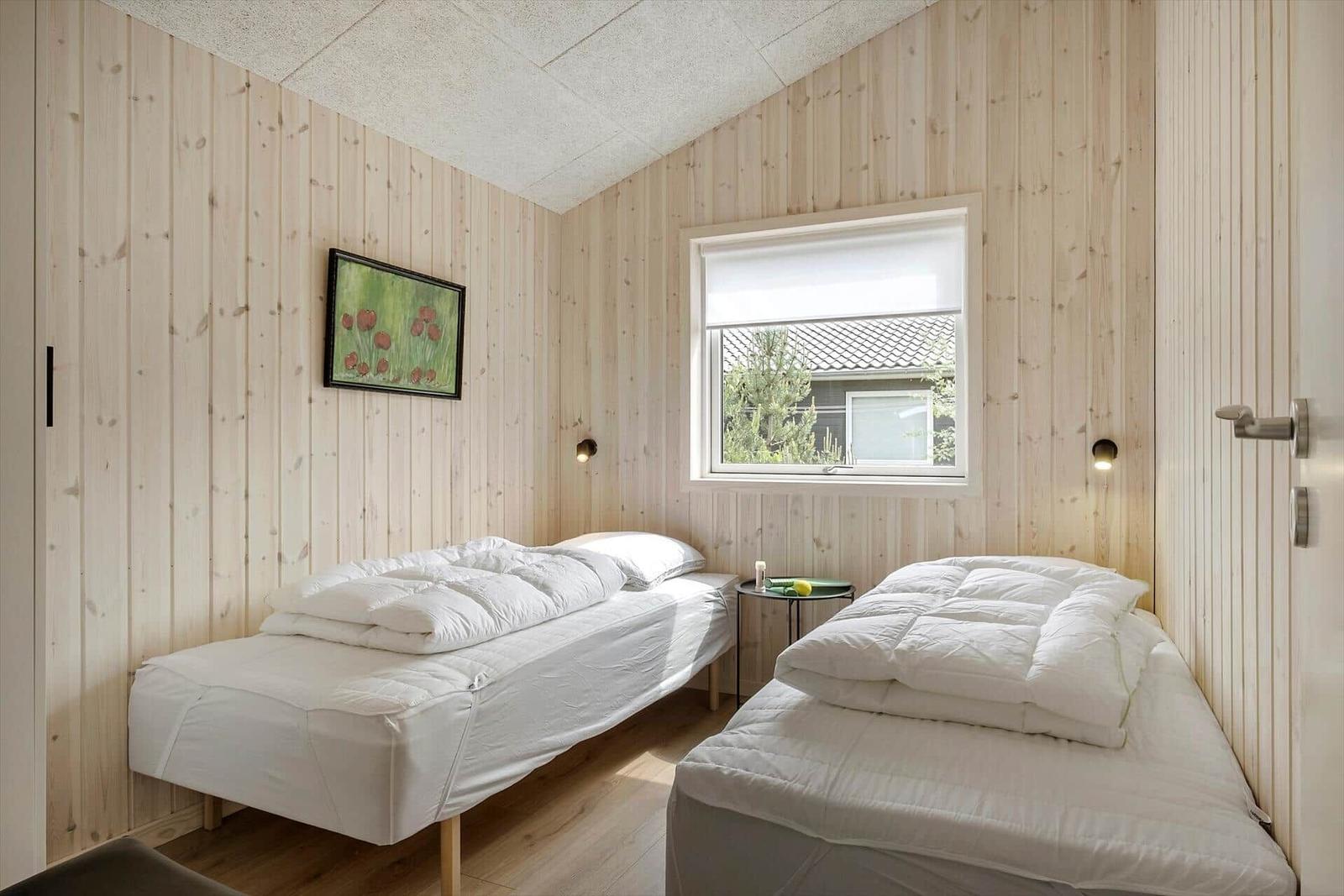 Zwei Betten mit weißen Bettwäsche, Holzwände und ein Fenster.