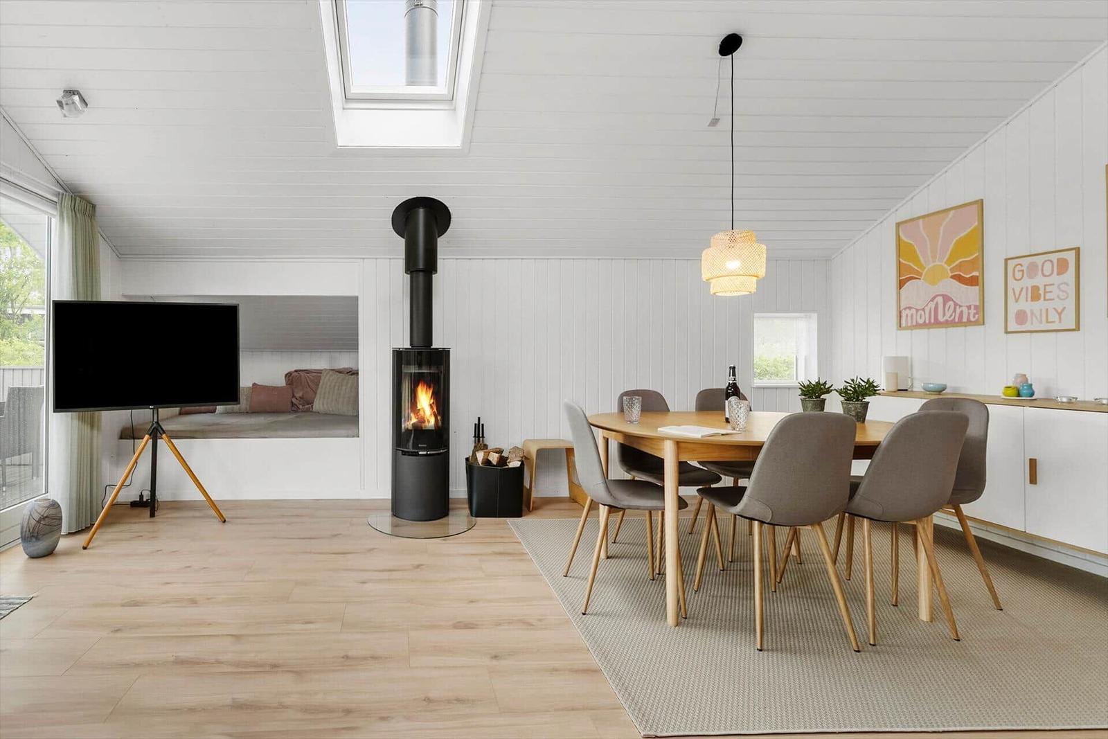 Wohn- und Essbereich mit Holzfußboden, Esstisch, Kamin und Fernseher.