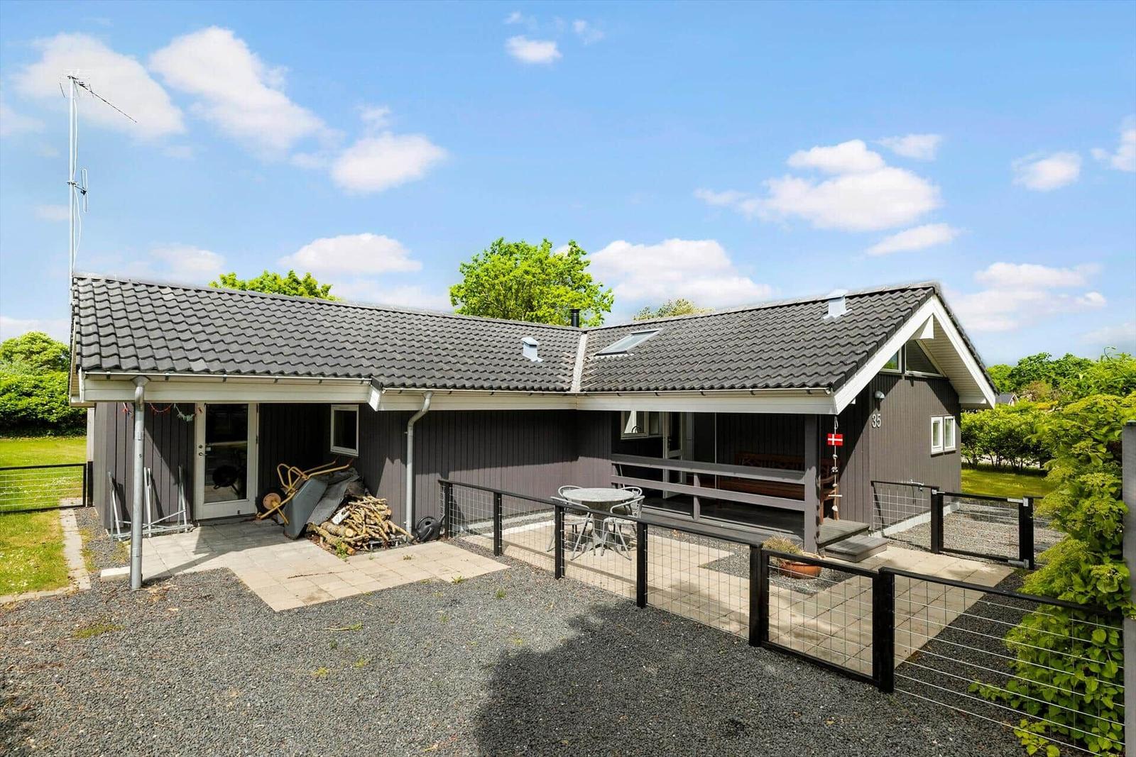 Ein Haus mit Terrasse, Grillplatz und Garten. Hausnummer 35. Dänecksflagge an der Wand.