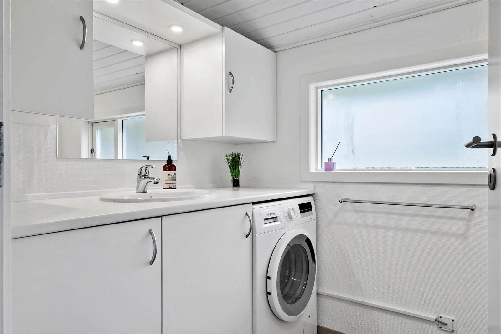 Badezimmer mit Waschmaschine und Spiegel an der Wand.