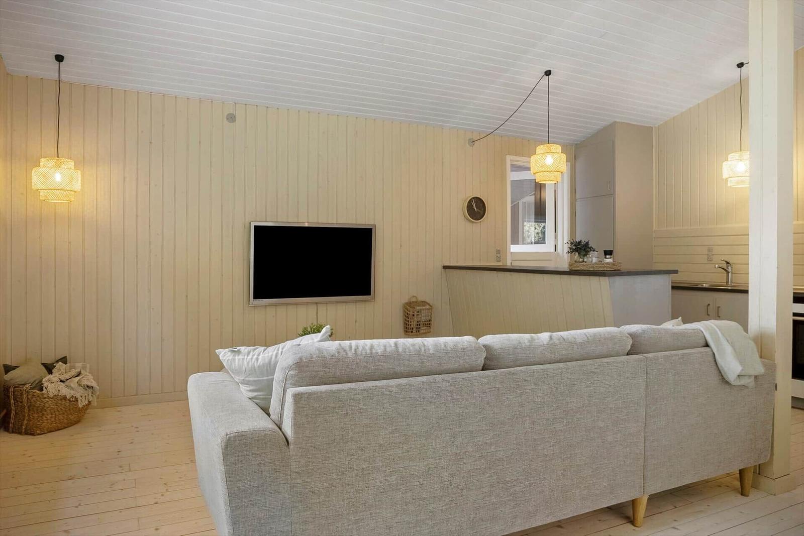 Wohnzimmer mit Sofa, Fernseher und Küchenbereich.