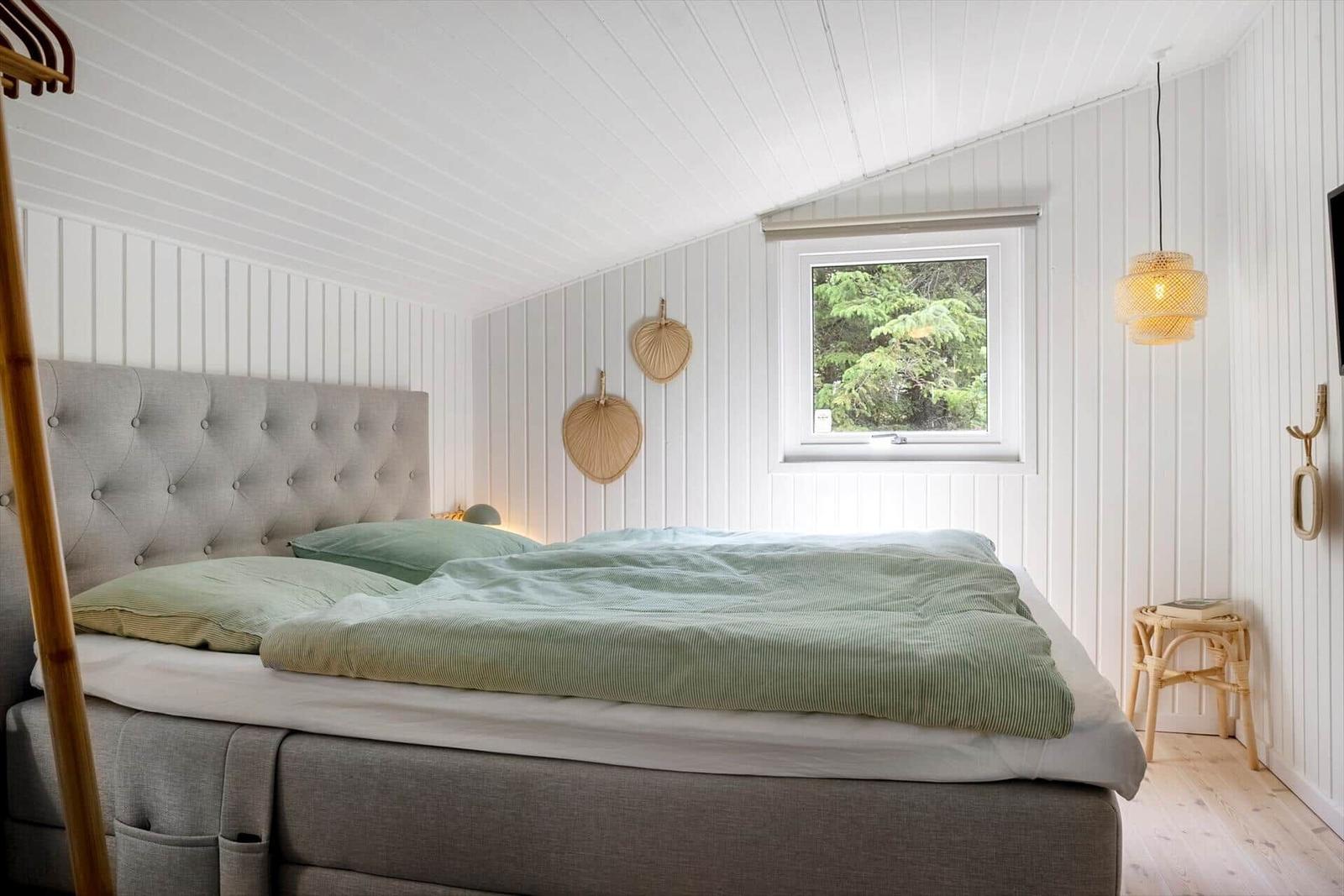 Schlafzimmer mit Bett, Fenster und Hängelampe.