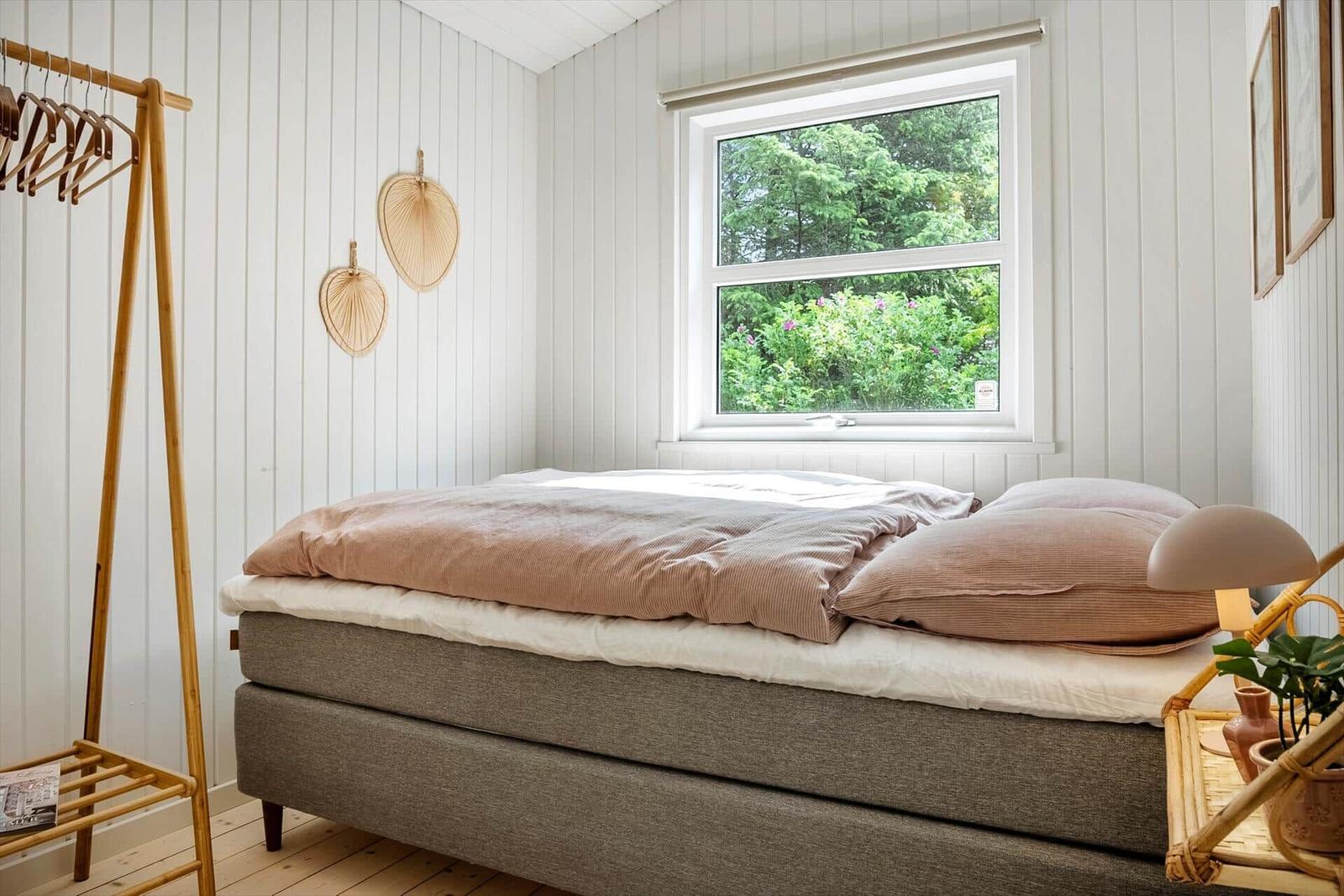Schlafzimmer mit Bett, Fenster und Kleiderständer.
