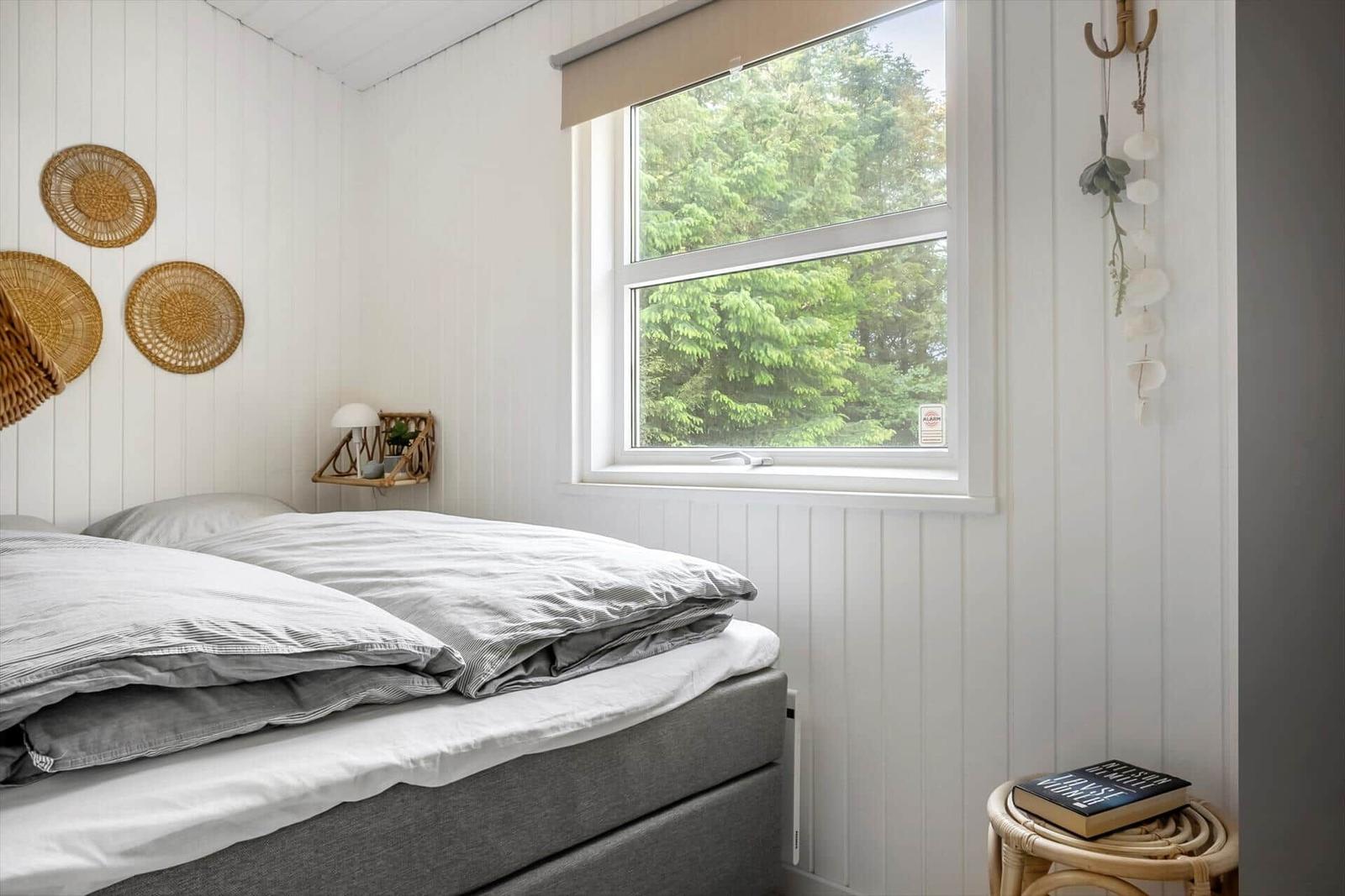 Schlafzimmer mit Bett, Fenster und Wanddekoration.
