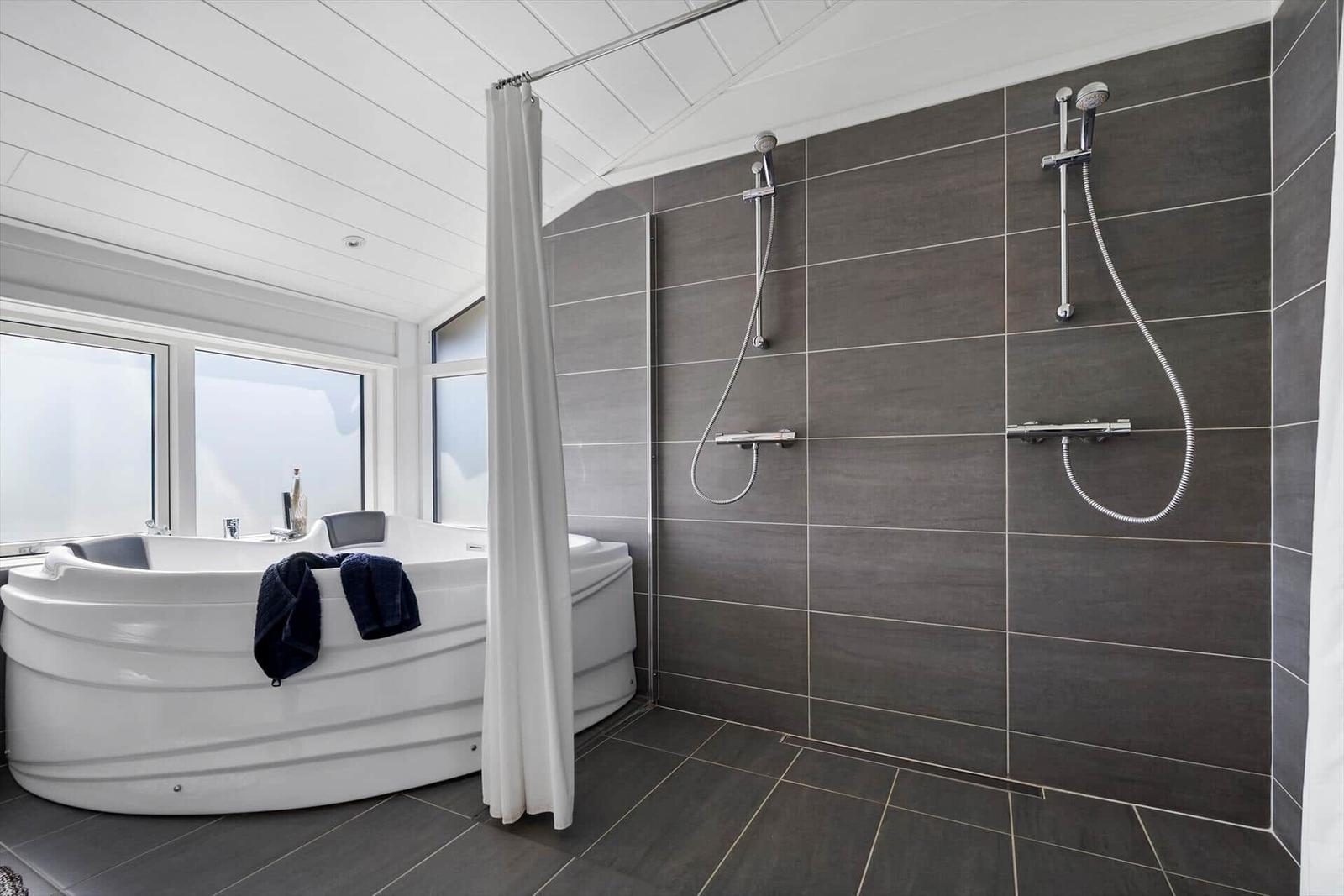 Bad mit Whirlpool, Dusche und großen Fenstern.