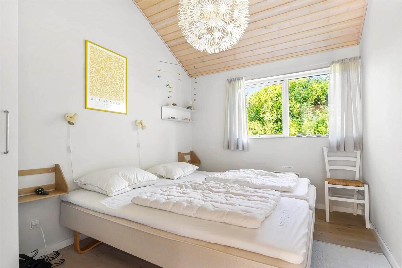 Schlafzimmer mit Doppelbett, Fenster und Holzdecke.