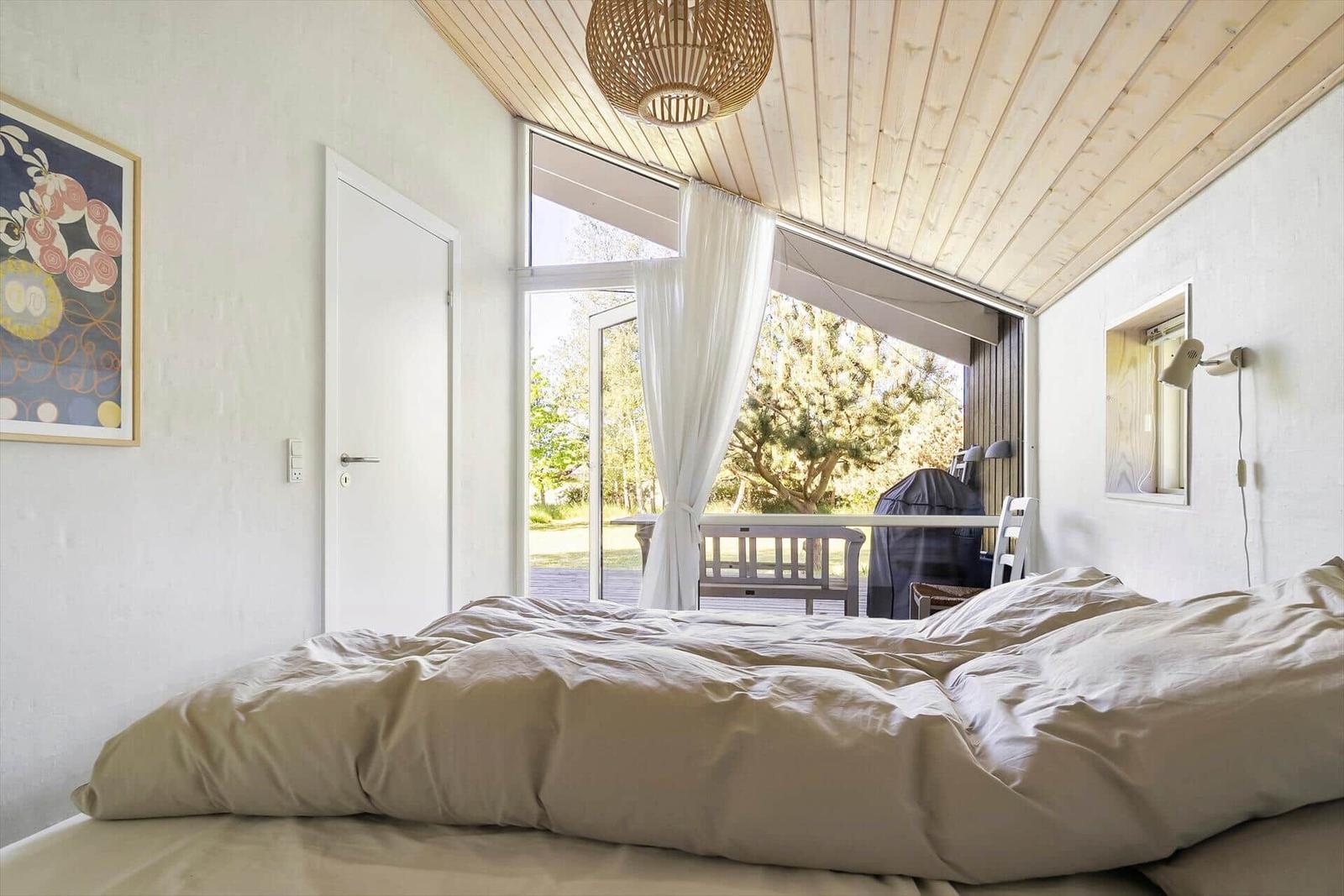 Schlafzimmer mit Bett, Fenster und Decke aus Holz.