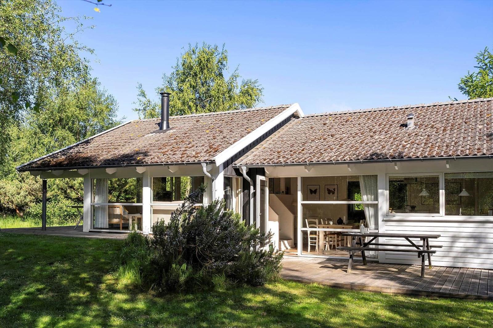 Wohnhaus mit Terrasse, Grillplatz und Garten. Fenster zeigen Wohn- und Essbereich.
