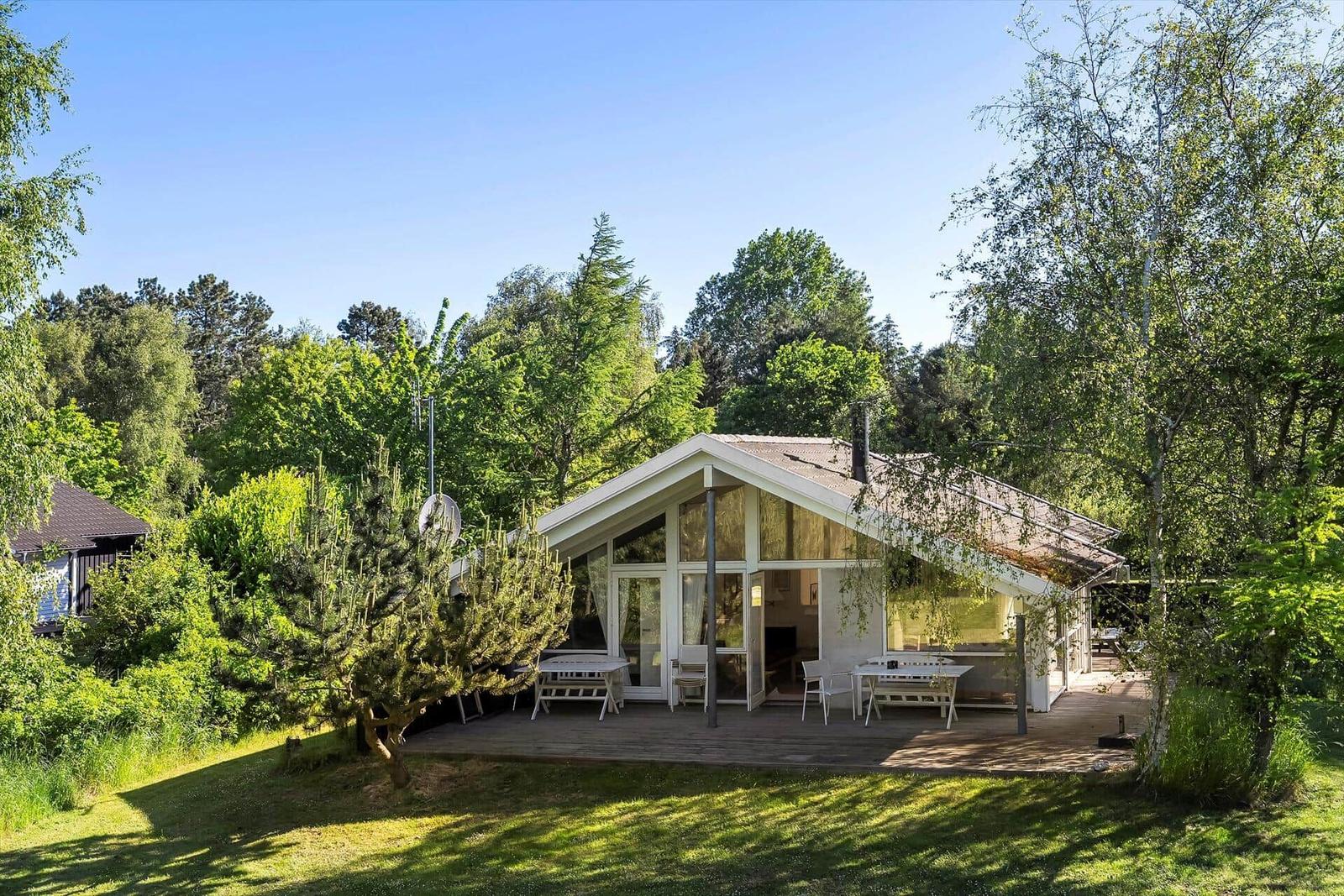 Moderne Villa mit Terrasse und Garten. Umgeben von Bäumen und Grünflächen.