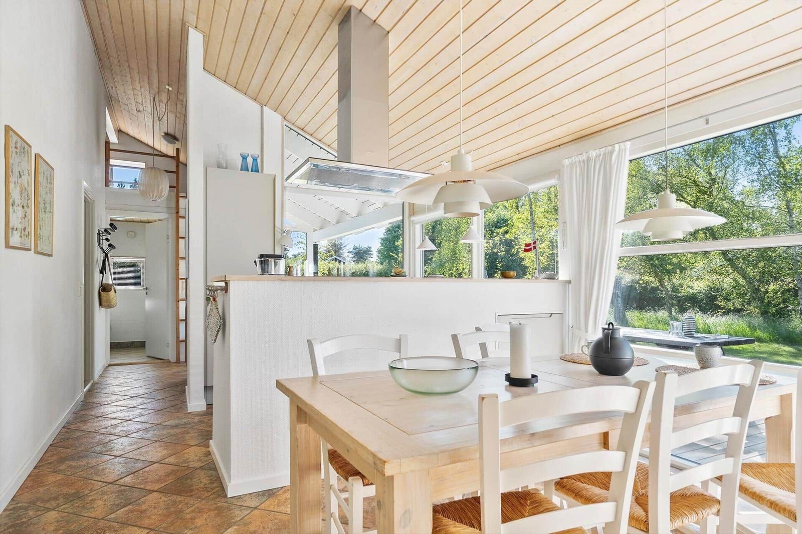 Küche mit Essbereich, Holzdecke und großem Fenster zum Garten.