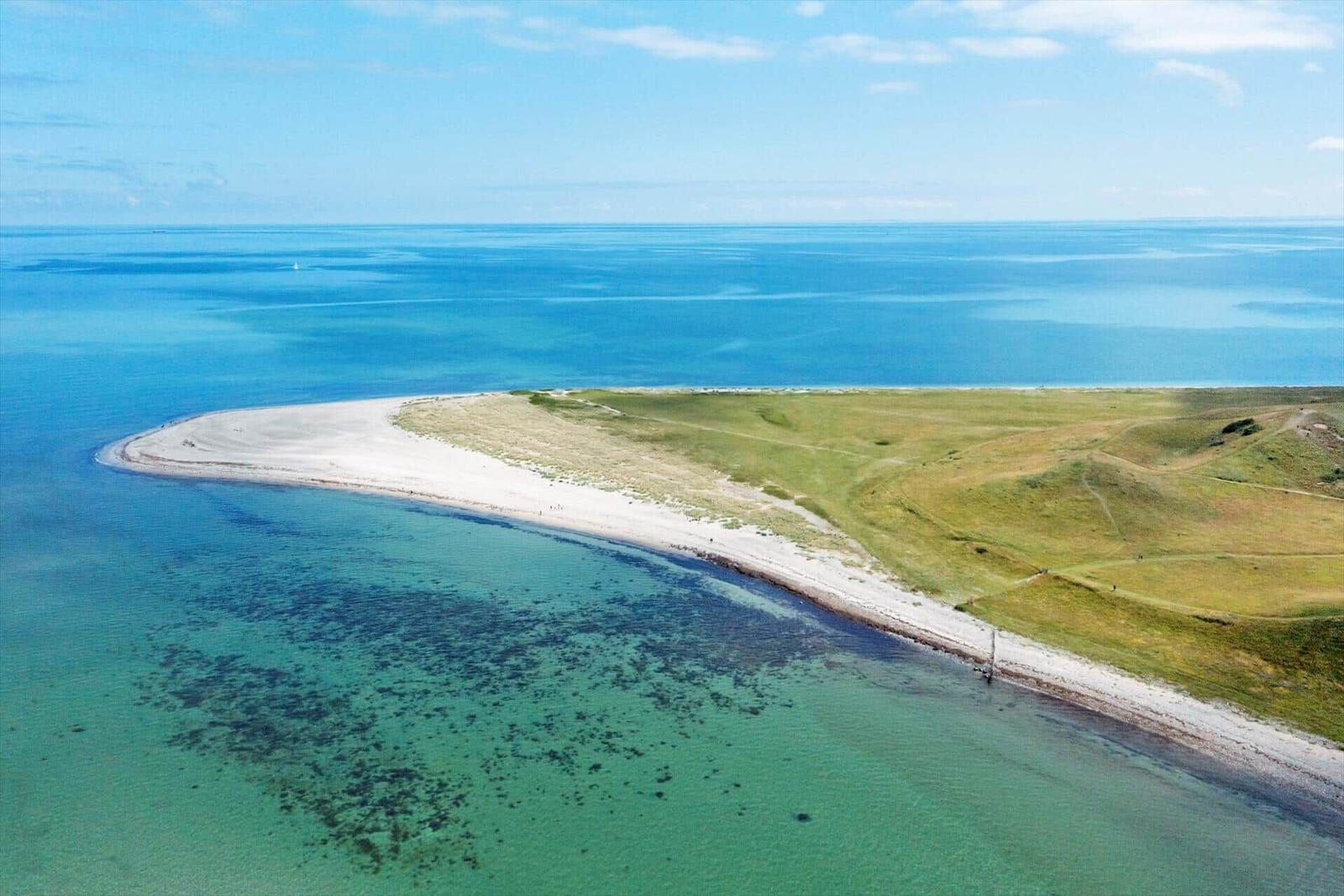 Aerielansicht einer Halbinsel mit Strand und grünen Hügeln an der Küste.