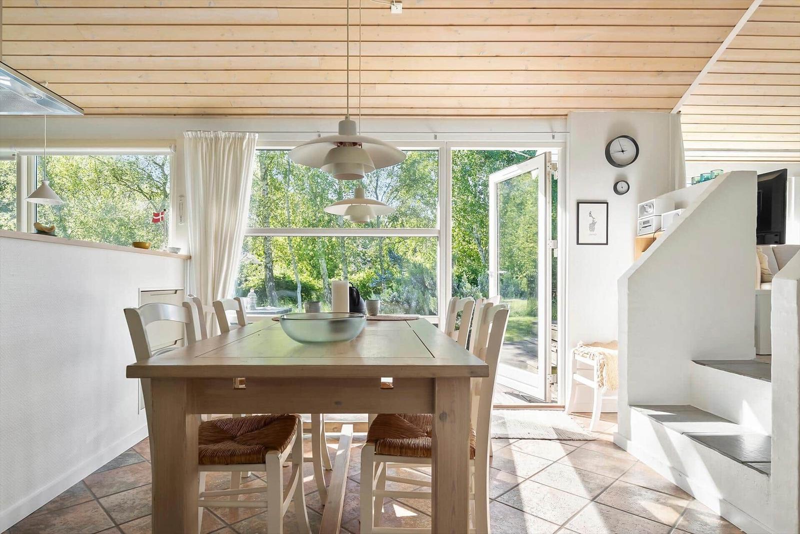 Esszimmer mit Holztisch, Stühlen und Blick auf Garten.