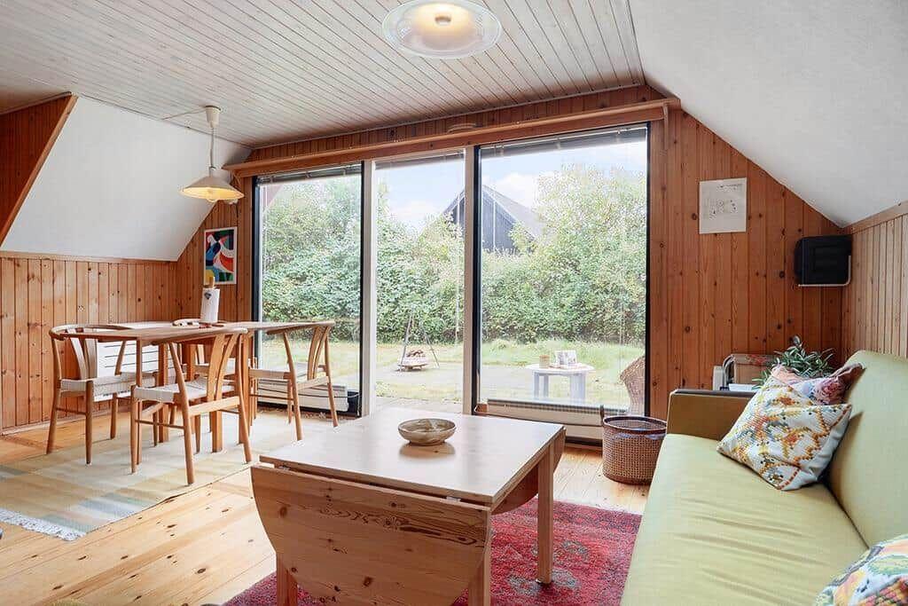 Wohn- und Essbereich mit Holzmöbeln und großen Fenstern zum Garten.