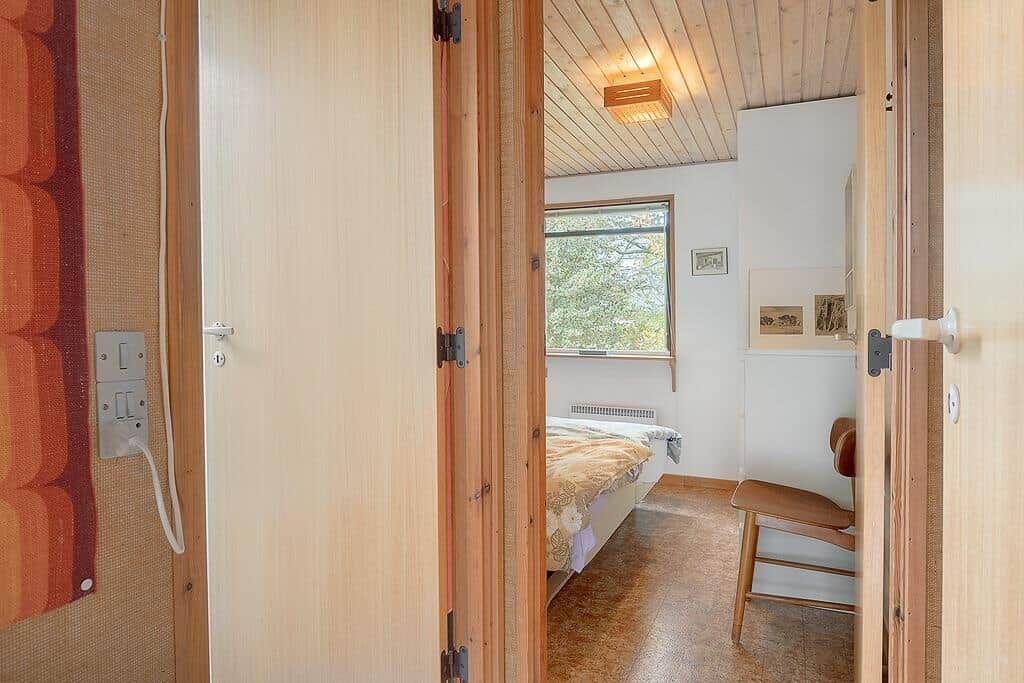 Schlafzimmer mit Bett, Stuhl und Fenster. Holzwände und Decke.