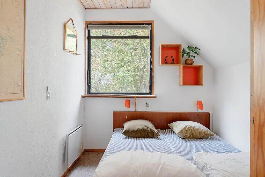 Schlafzimmer mit Dachschrägen, Fenster und Bett mit Kissen.