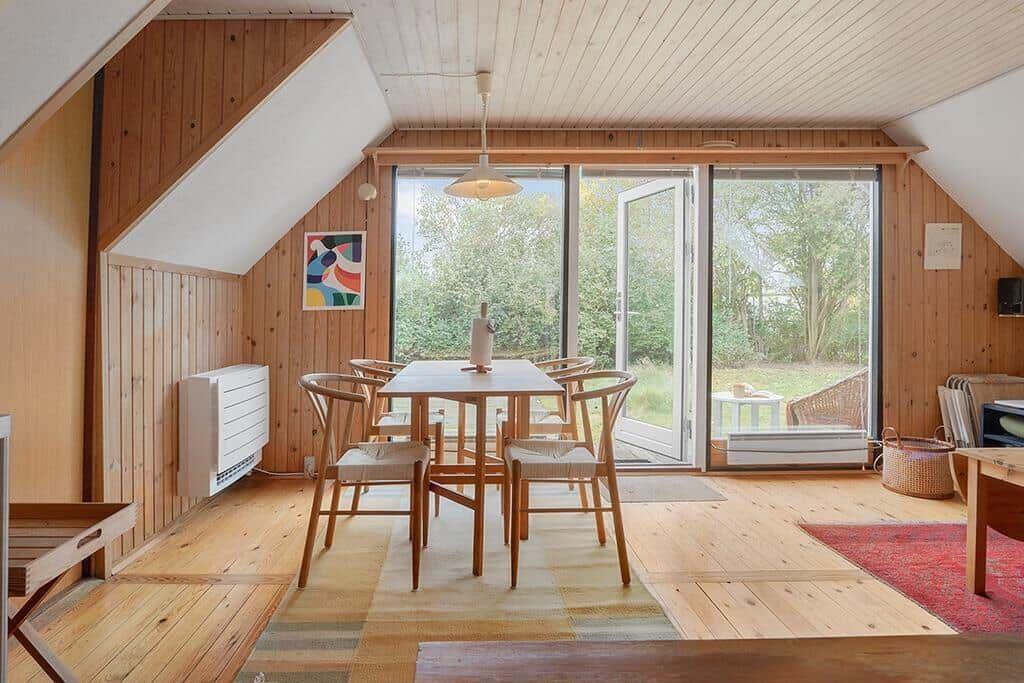 Esszimmer mit Holztisch, Stühlen und Glasfront zum Garten