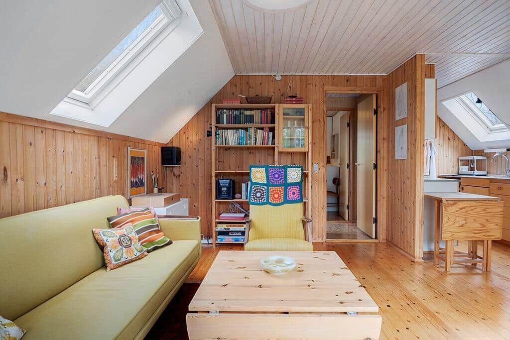 Wohnzimmer mit Sofa, Couchtisch und Bücherregal unter Dachschrägen.