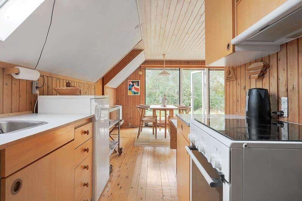 Küche mit Holzwand und Blick auf Essbereich mit Tisch und Stühlen.