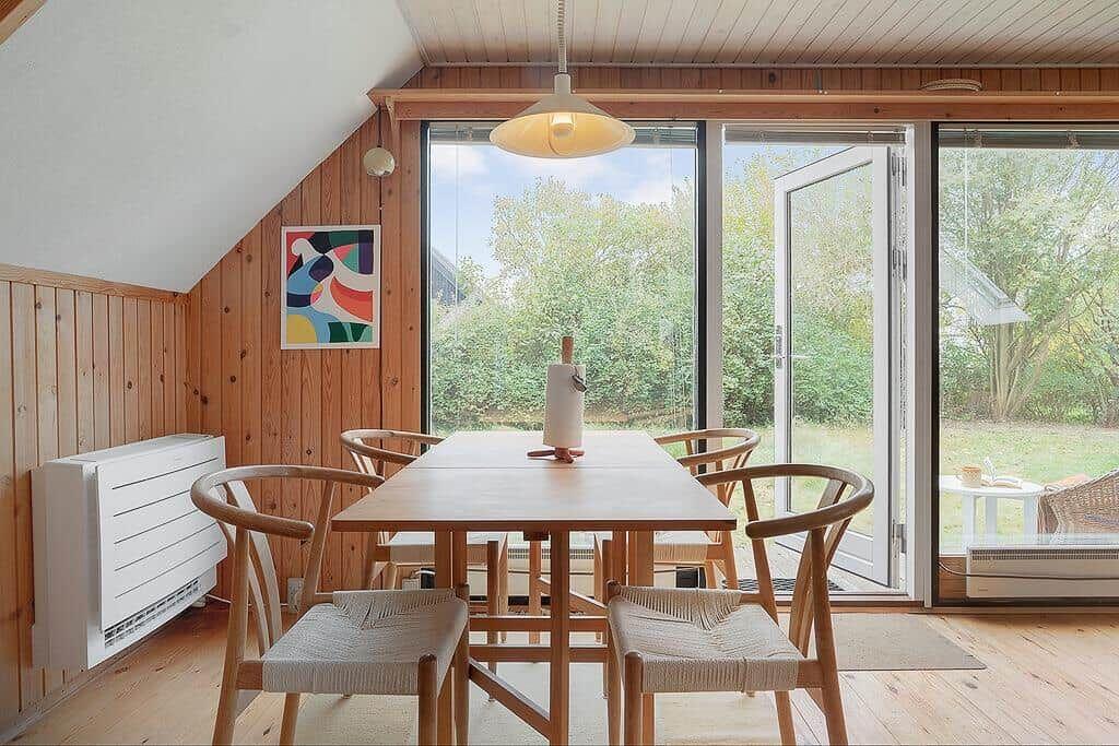 Essbereich mit Holztisch, Stühlen und Glasfront zur Außenterrasse.