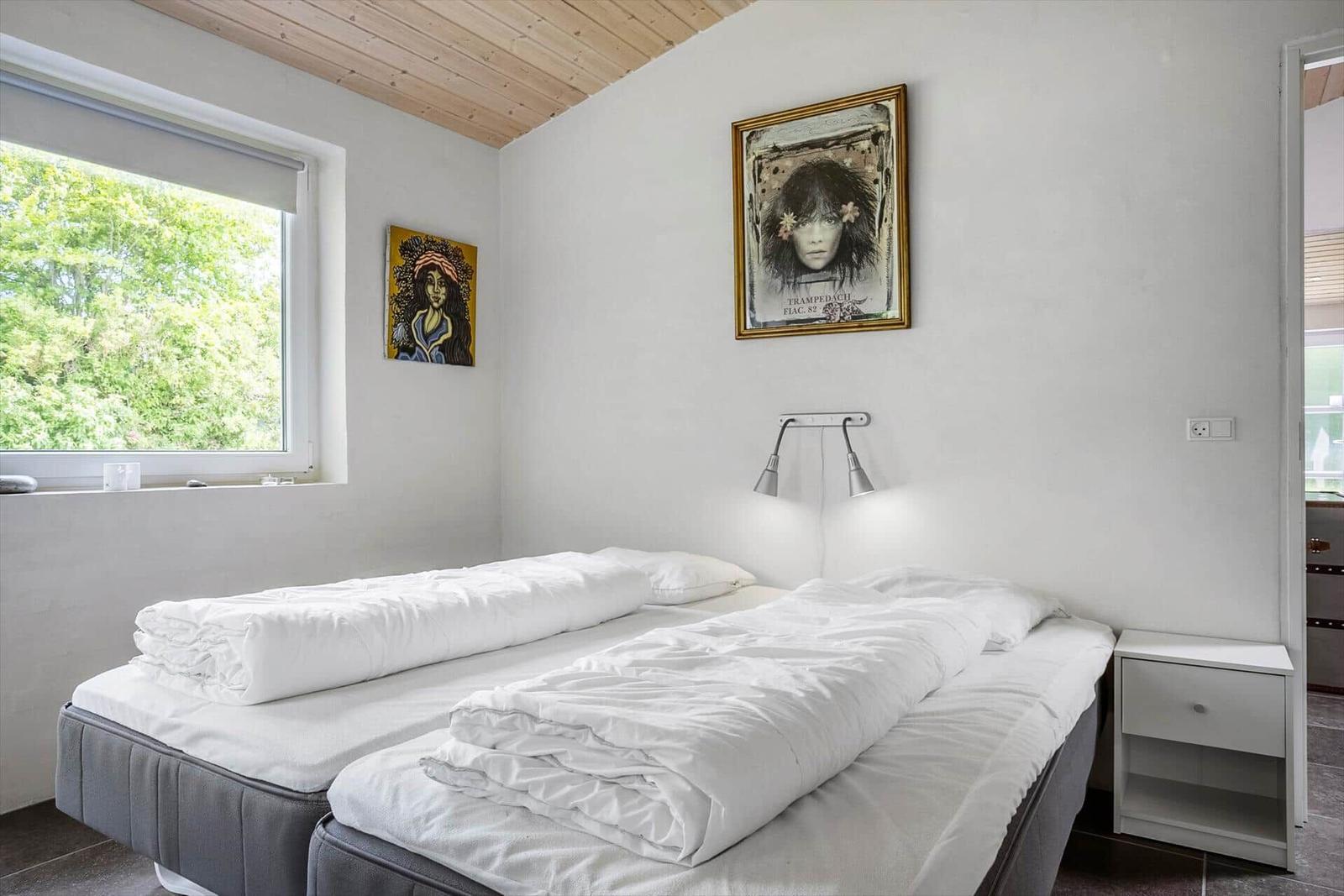 Bedroom with double bed, window, and wall pictures.