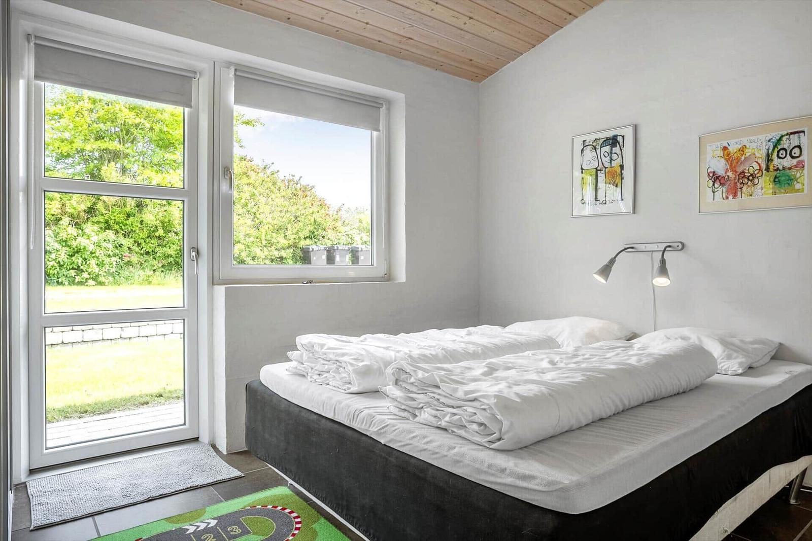 Bedroom with bed, windows, and wall art.
