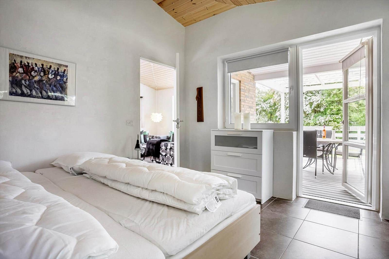 Bedroom with bed, dresser, and access to terrace.