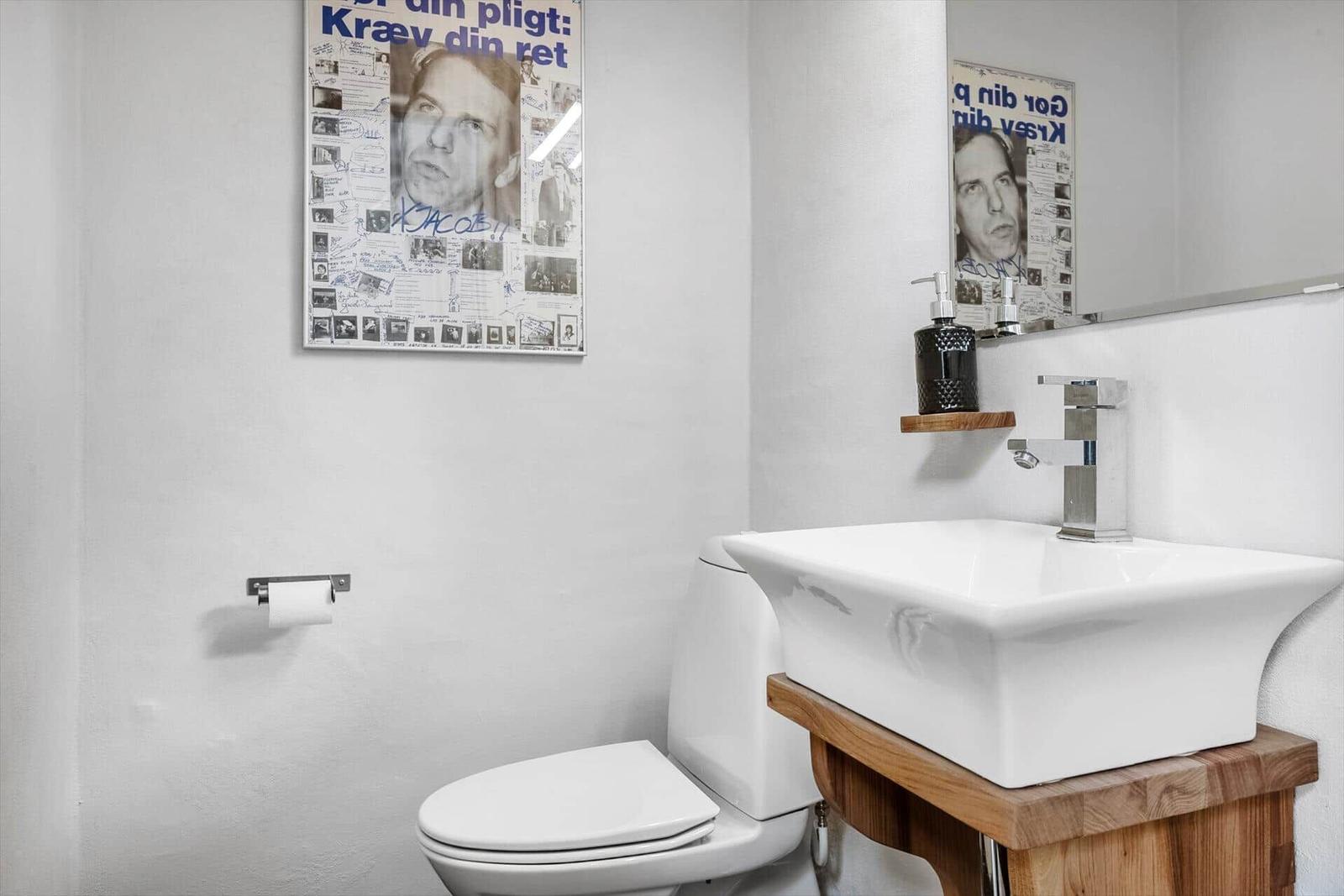 Bathroom with toilet, sink, and wall poster.