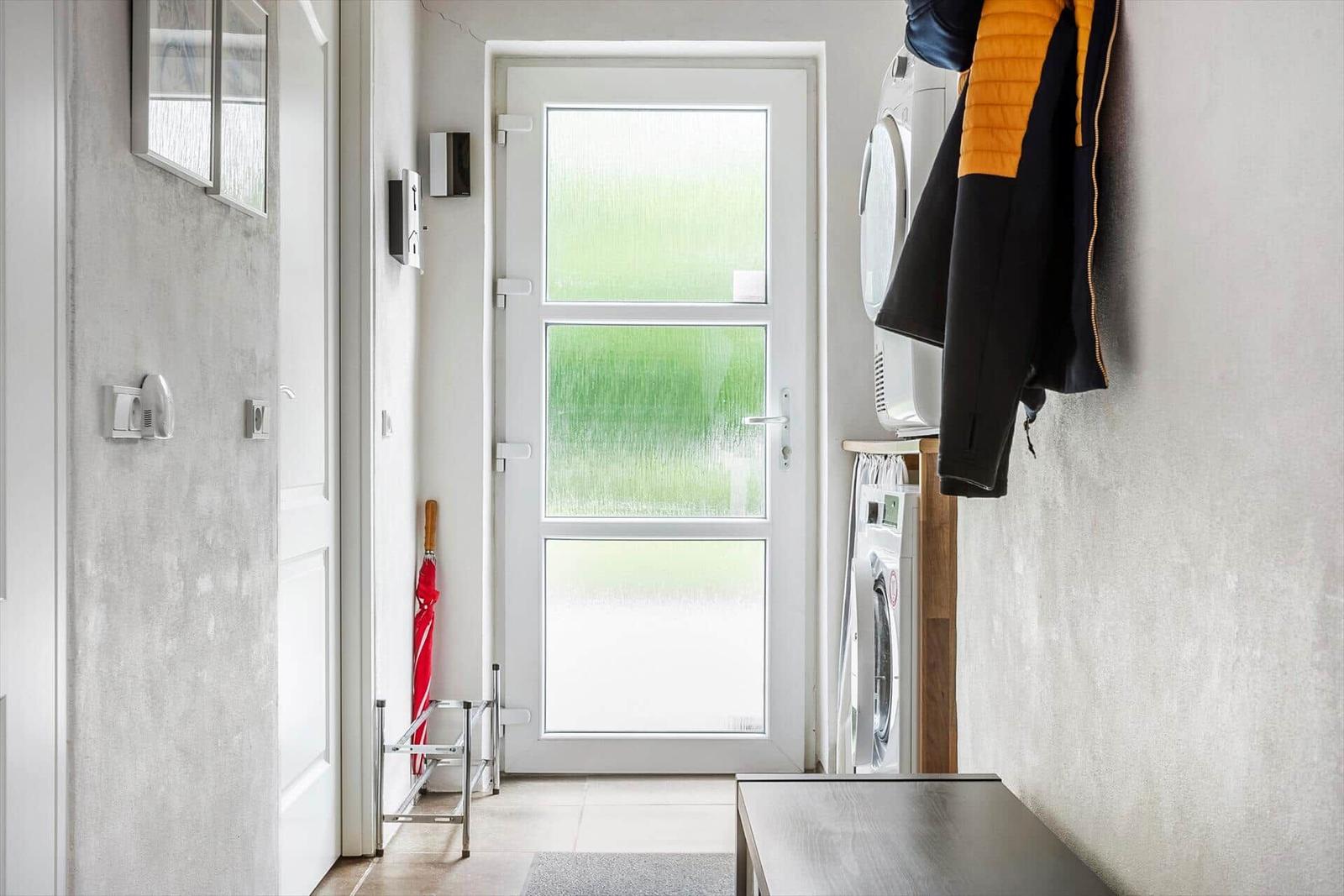 Entrance area with washing machine, coat rack, and door with tinted glass.
