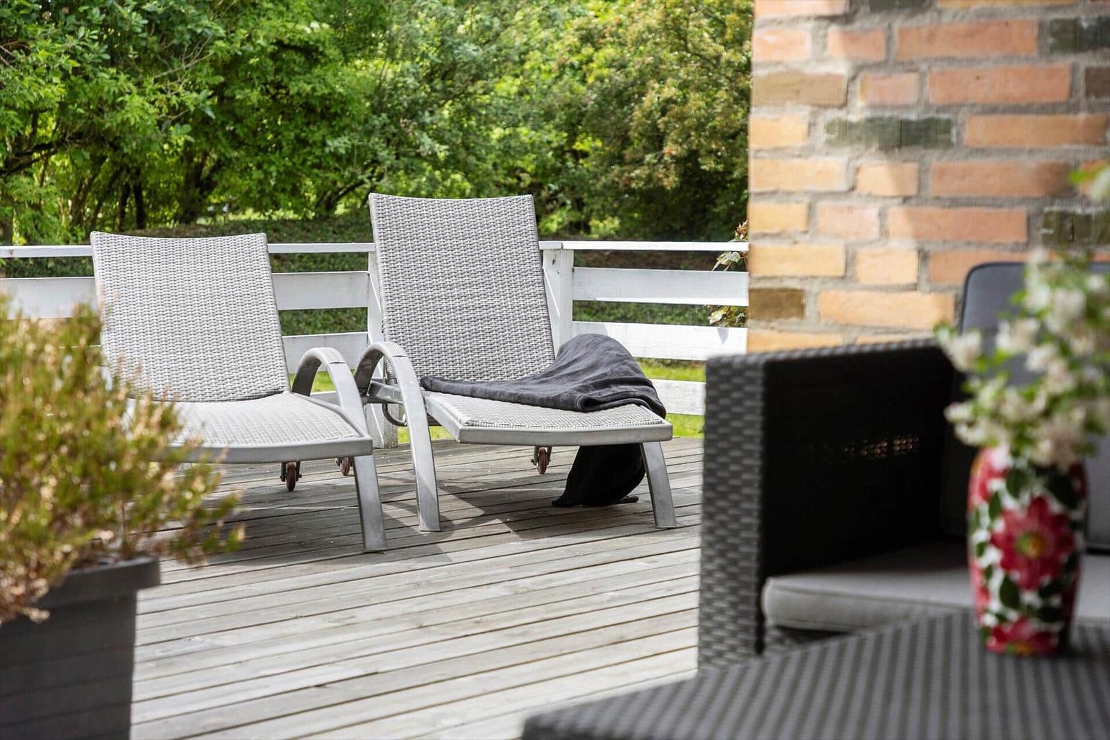 Deck with two lounge chairs, plants, and wooden flooring.