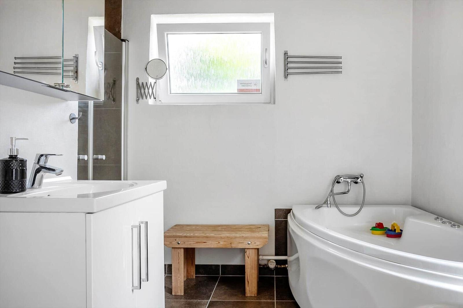 Bathroom with bathtub, sink, and wooden bench.