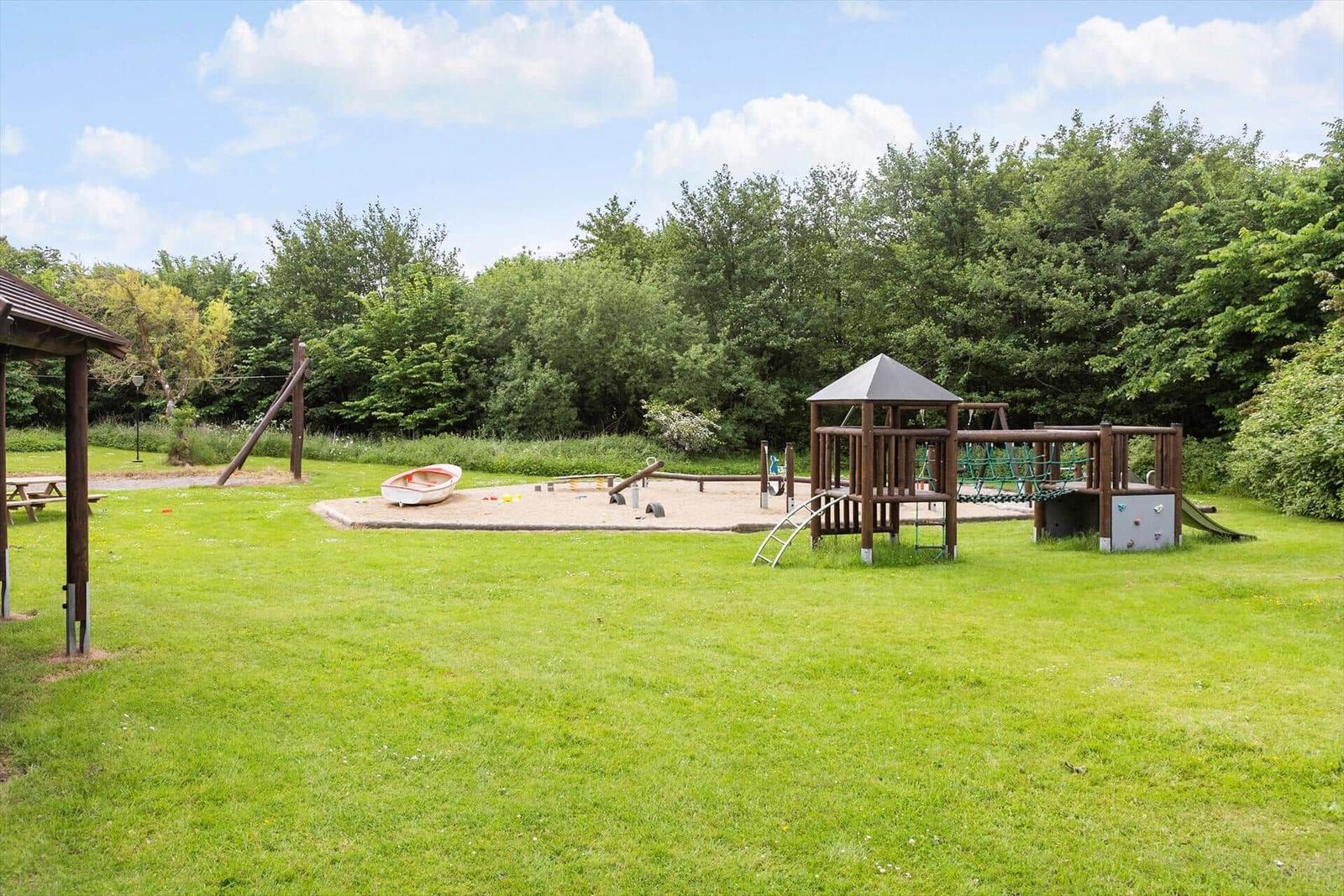 Large playground with sandbox, climbing frame, and slide on green lawn.