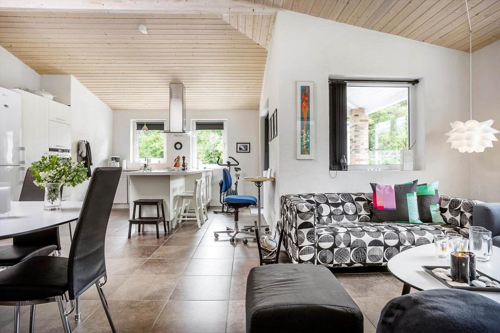 Living and kitchen area with sofa, dining table, and windows.