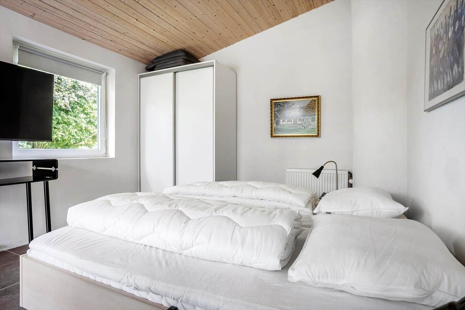 Bedroom with bed, wardrobe, and window with view of greenery.
