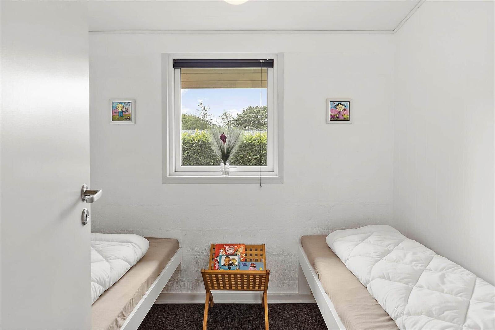 Two single beds with white covers face a window.