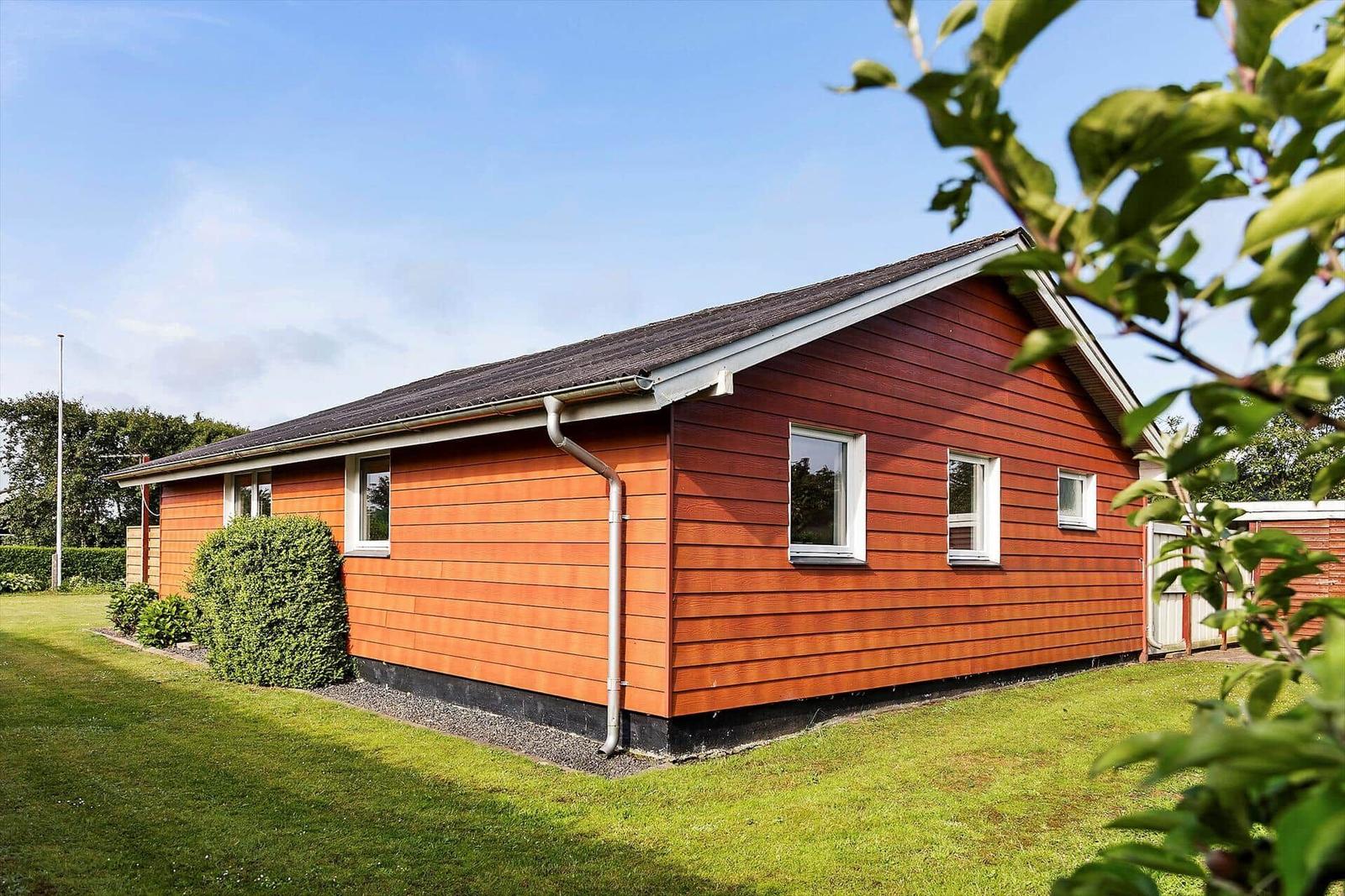 A house with orange cladding and green lawn.
