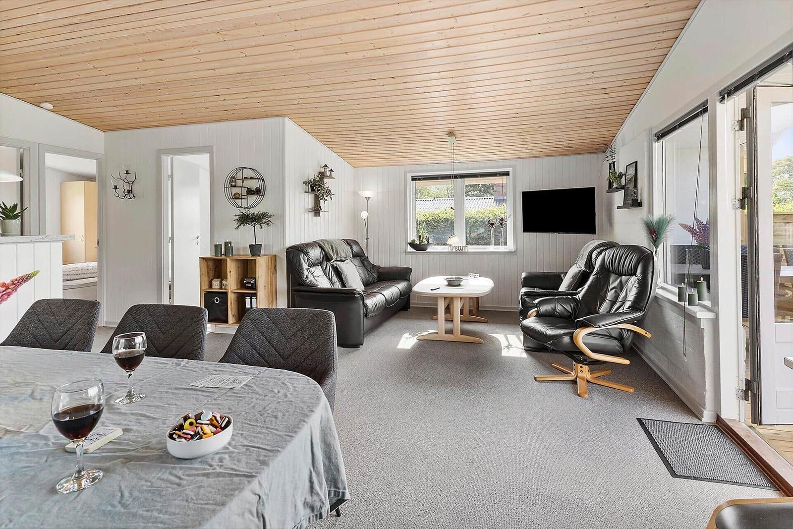 Living and dining area with sofa, chairs, table, and windows.