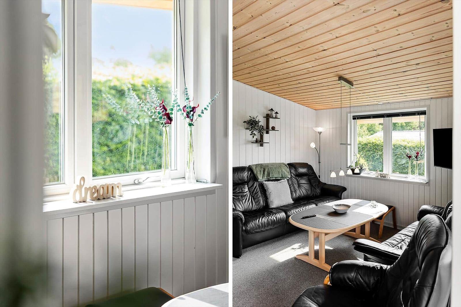 Living room with leather sofa, wooden table, and green view through window.