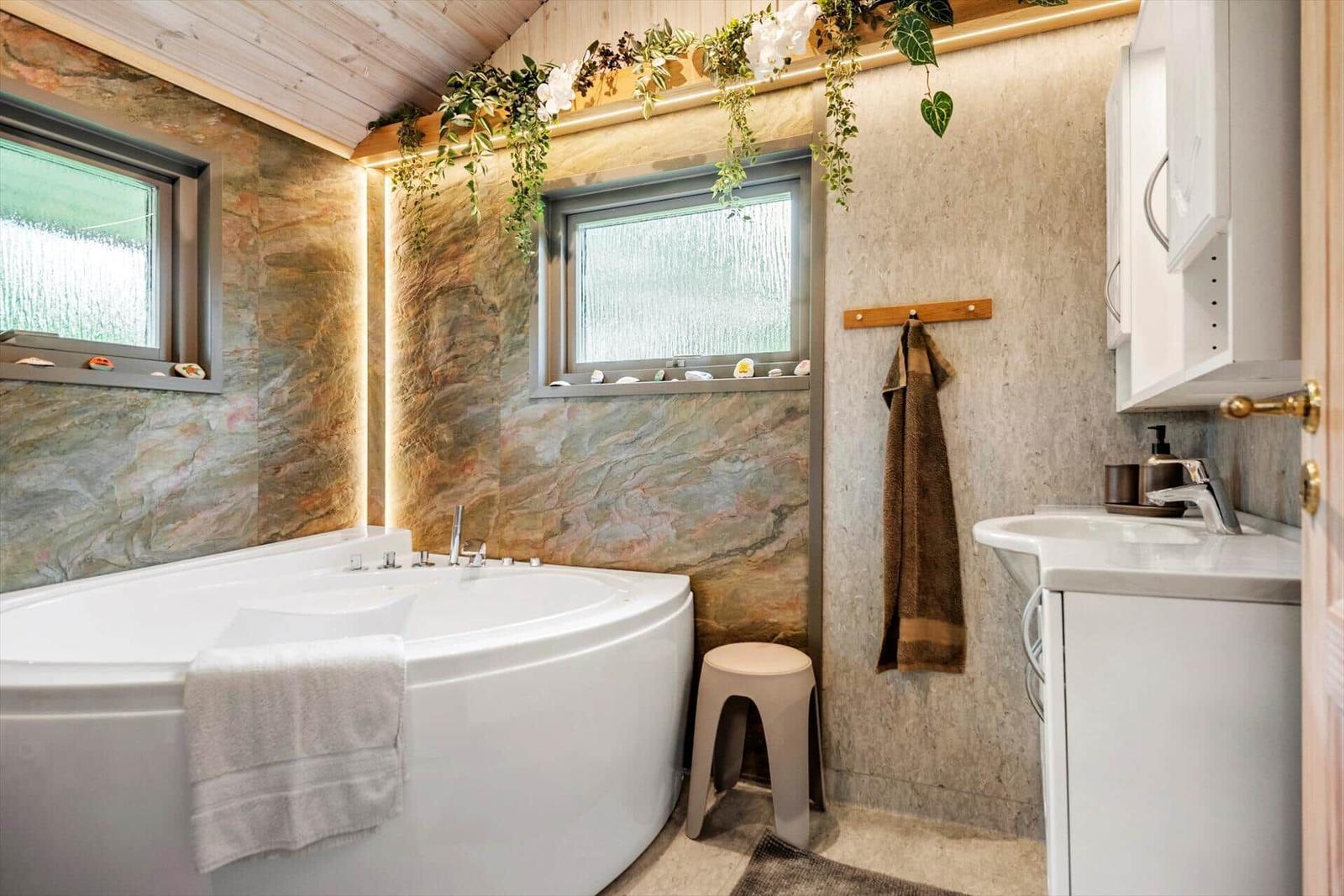 Badezimmer mit Badewanne, Waschbecken und Pflanzen an der Decke.