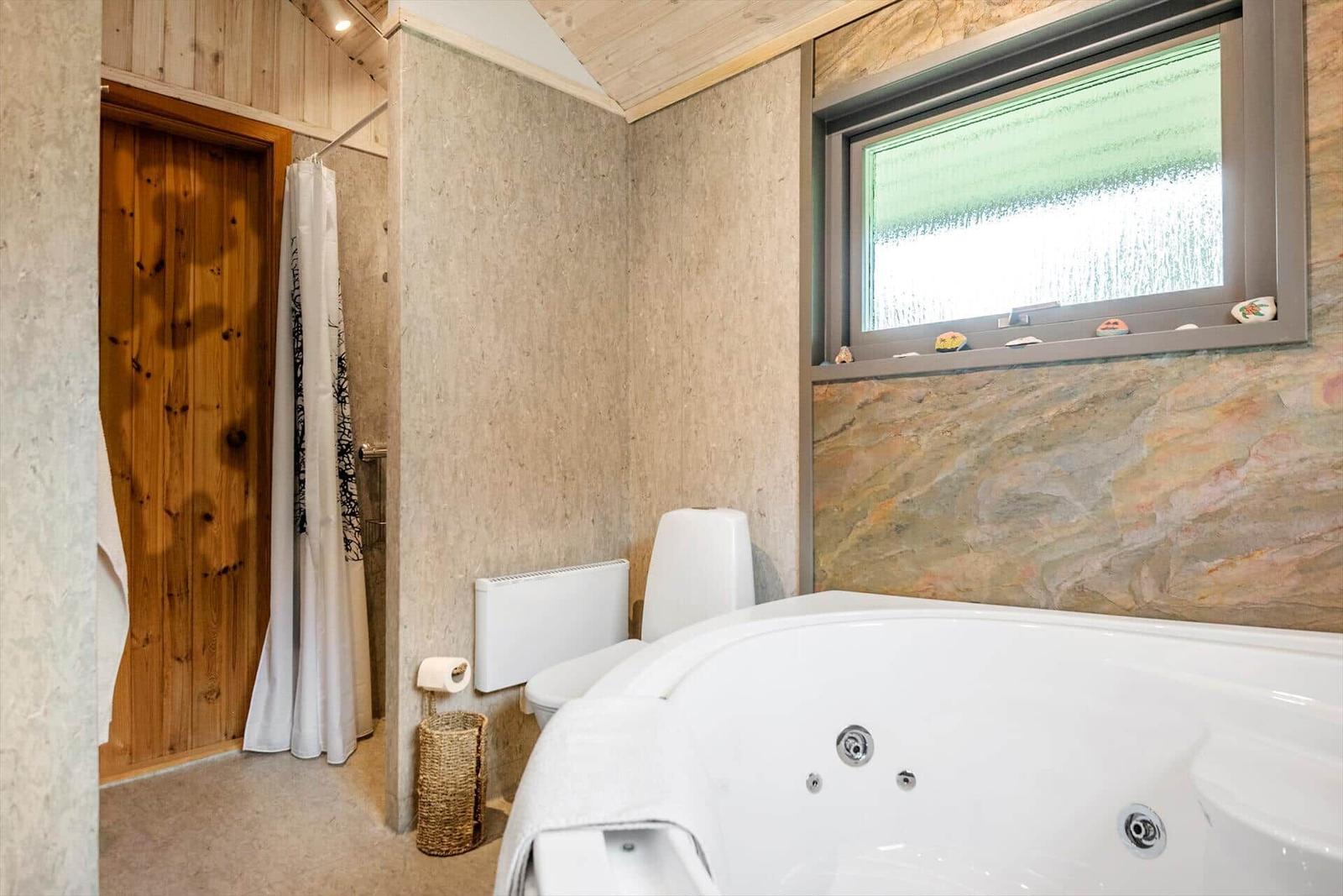 Bad mit Whirlpool, Toilette und Dusche mit Holztür.