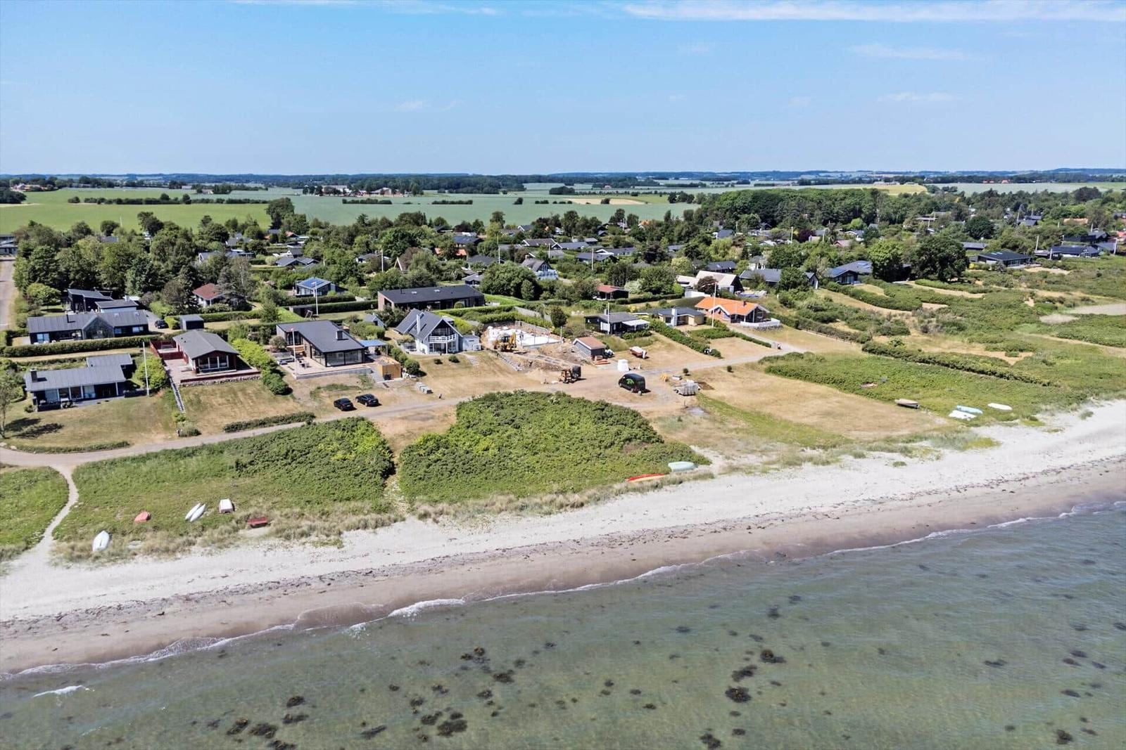 Strandnahe Ferienhäuser mit Blick aufs Meer und grüne Landschaft.