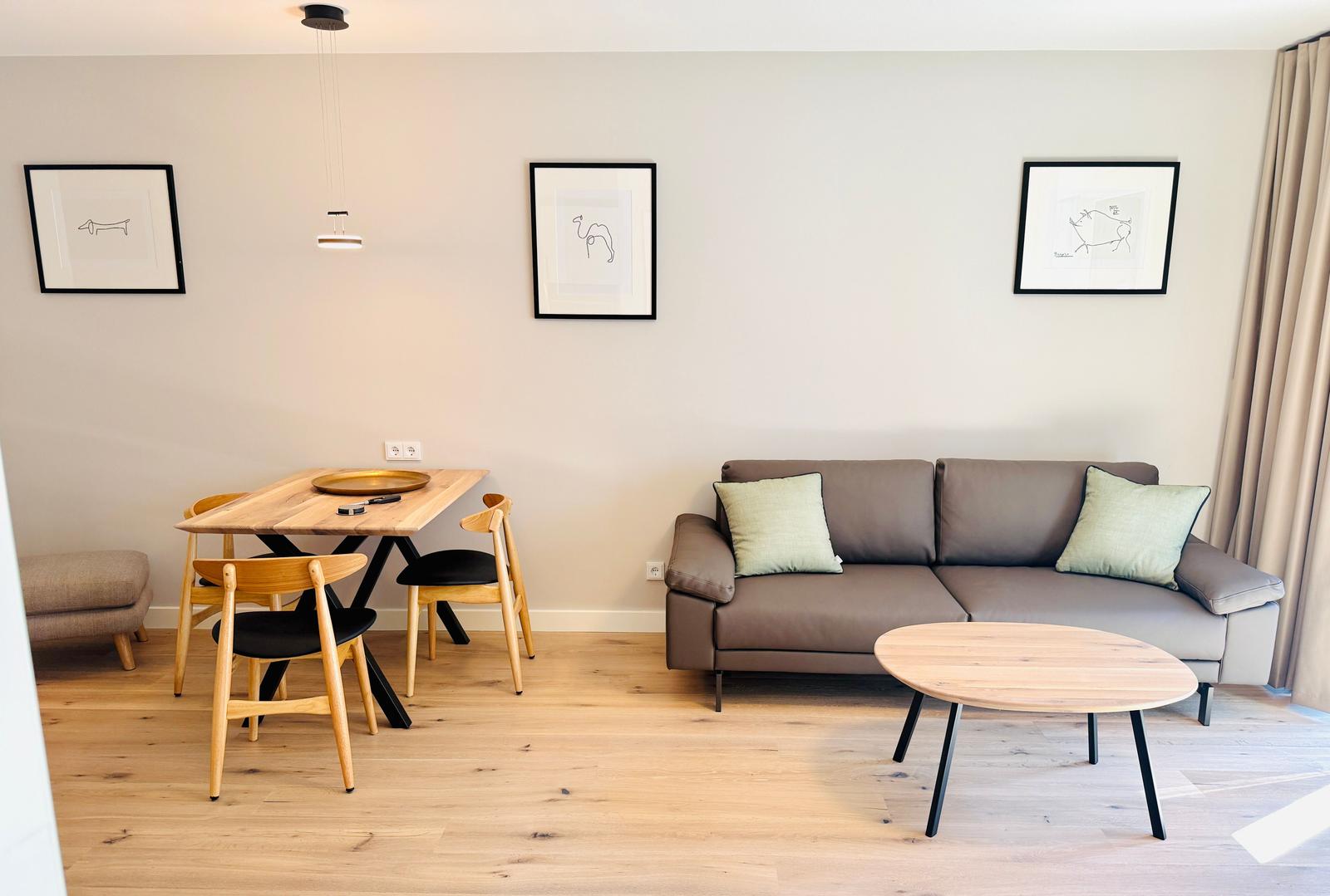 Wohn- und Essbereich mit Sofa, Tisch und Stühlen an Holzboden.