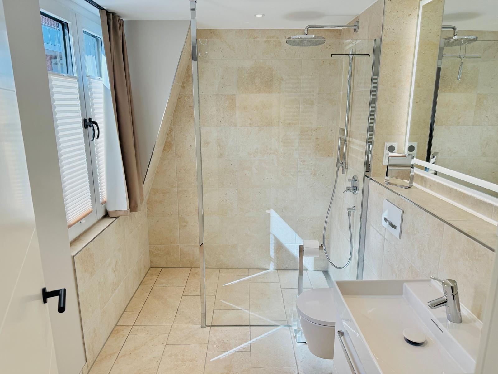 Badezimmer mit Dusche, Toilette und Waschbecken. Fenster mit Jalousie und Vorhang.