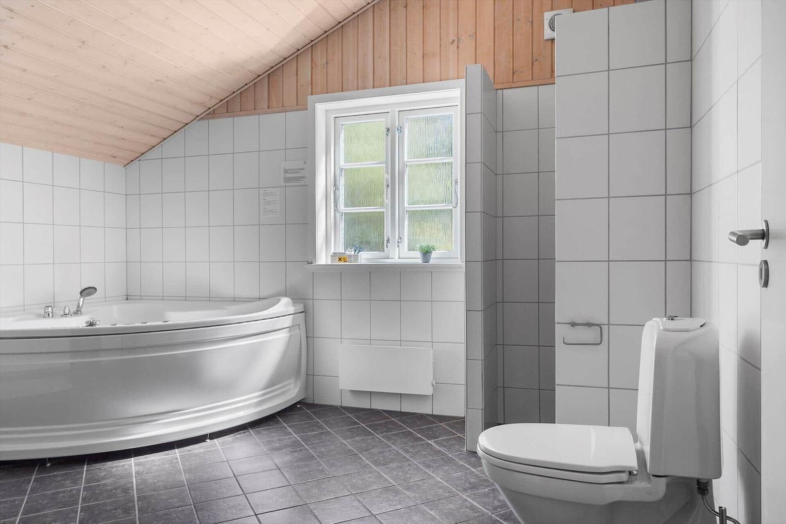 Badezimmer mit Badewanne, Toilette und Fenster