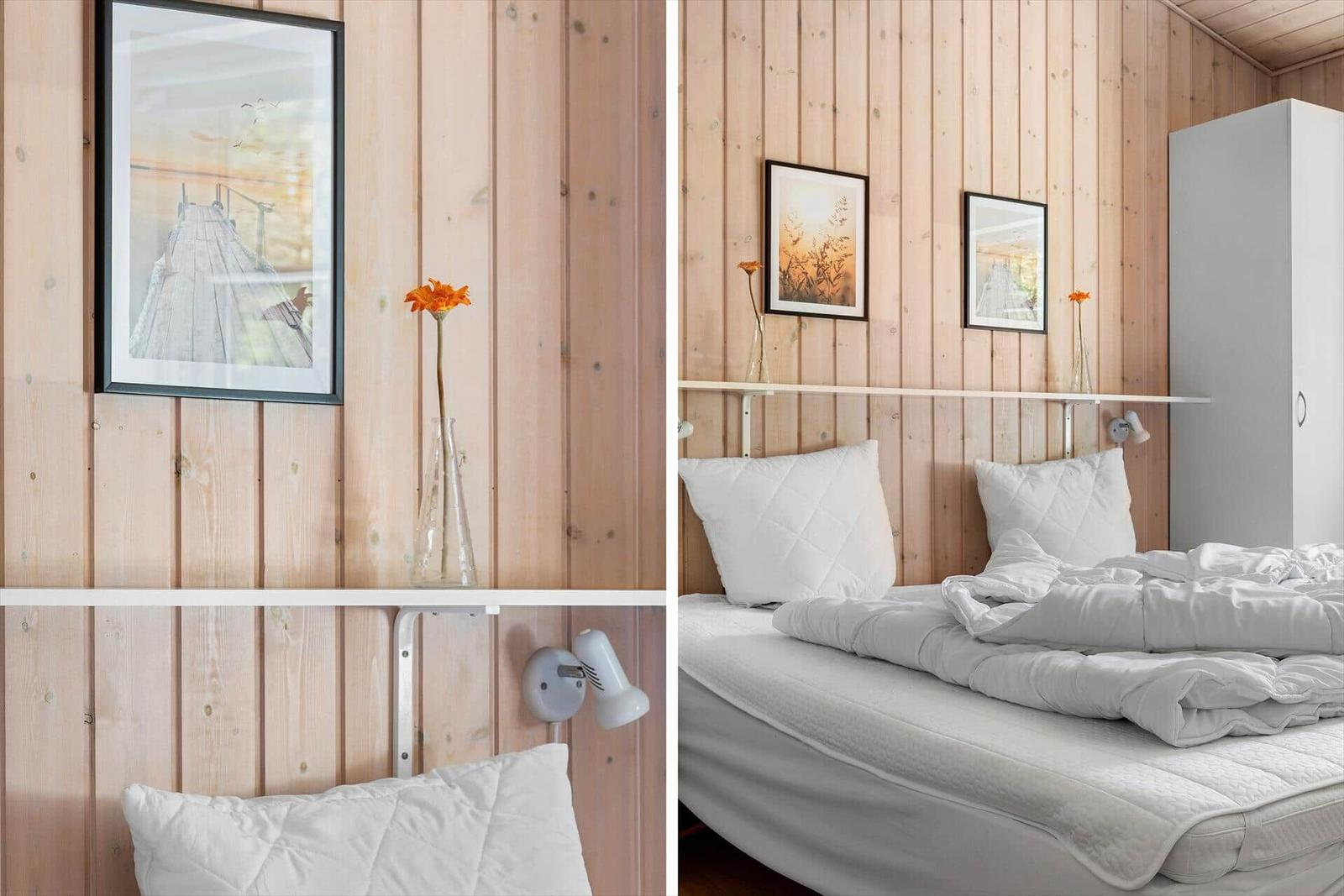 Schlafzimmer mit Holzwand, Bett, Kissen und Bildern.